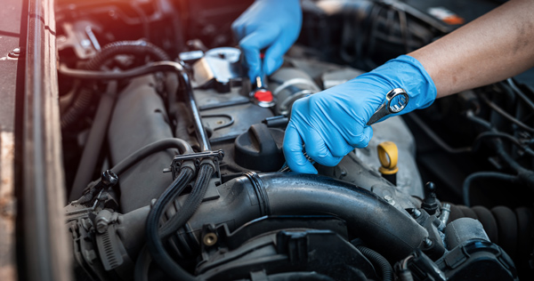 mechanic hands in latex gloves using tools in vehicle engine MOT testing