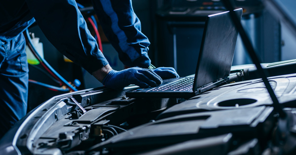 mechanic using laptop to run vehicle diagnostics