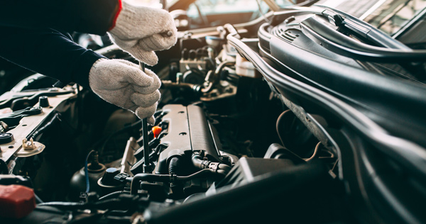 mechanic hands in vehicle engine undertaking maintenance and repairs
